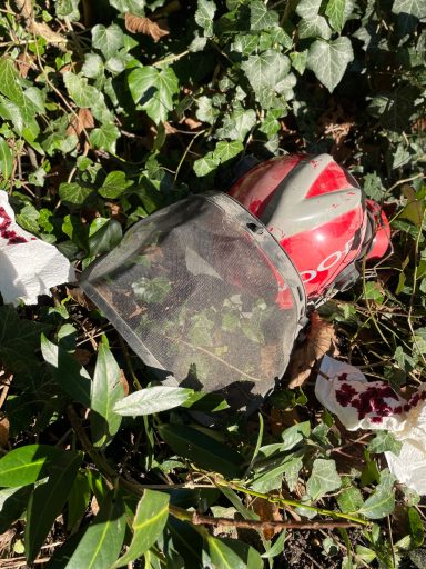 Ein beschädigter Forsthelm liegt im Gestrüpp