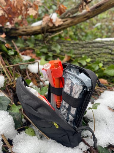 Ein genutztes individuelles First Aid Kit (IFAK) liegt in einer verschneiten Waldlandschaft