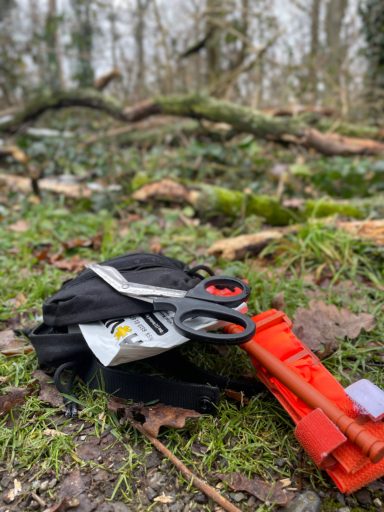 Ein genutztes kleines Individuelles First Aid Pack liegt offen im Wald 