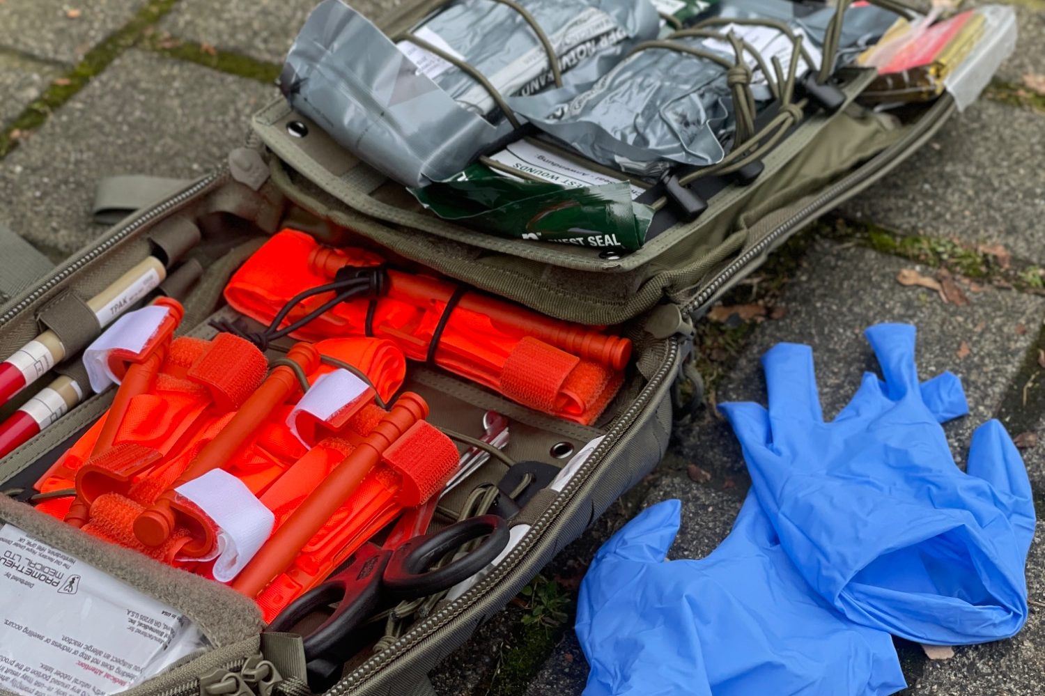 Ein Individuelles First Aid Kid (IFAK) liegt offen auf dem Boden. Der Inhalt liegt sichtbar offen. 