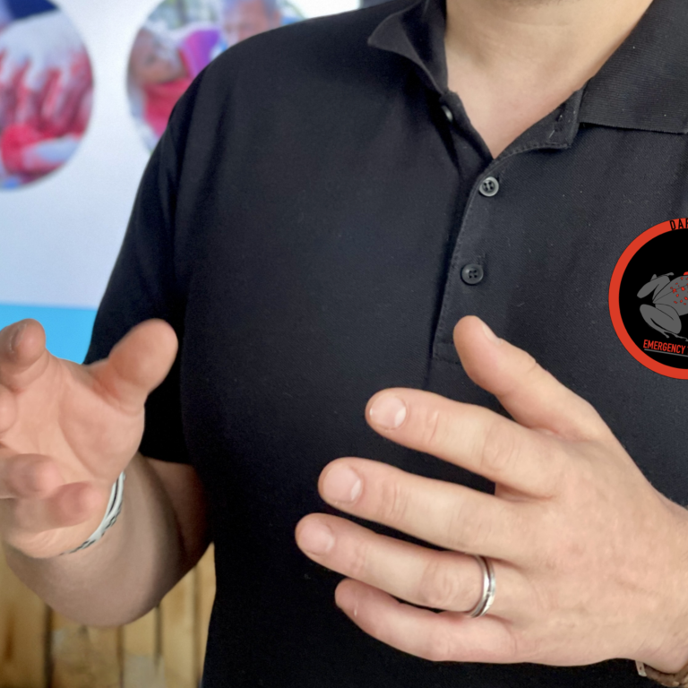 Dozent für Gesundheitsfachberufe Ein Mann erklärt etwas vor einer Tafel. Auf der Brust prangt das Logo von Dartfrog Emergency Training