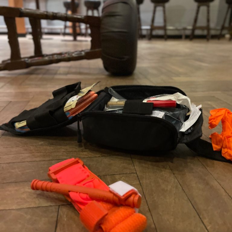 Ein geöffnetes individuelles First Aid Kid liegt vor einem umgestürzten Barhocker